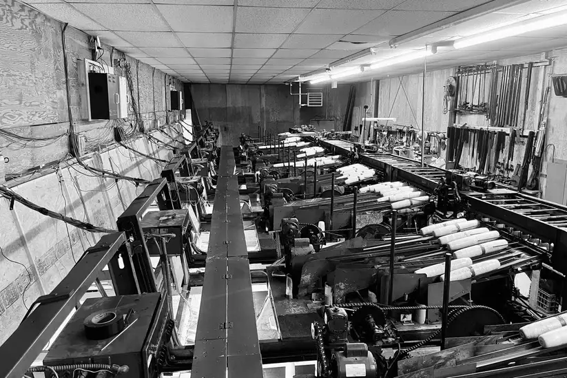 A black-and-white view down the length of the alley, with a row of pin-setting machines on each side.