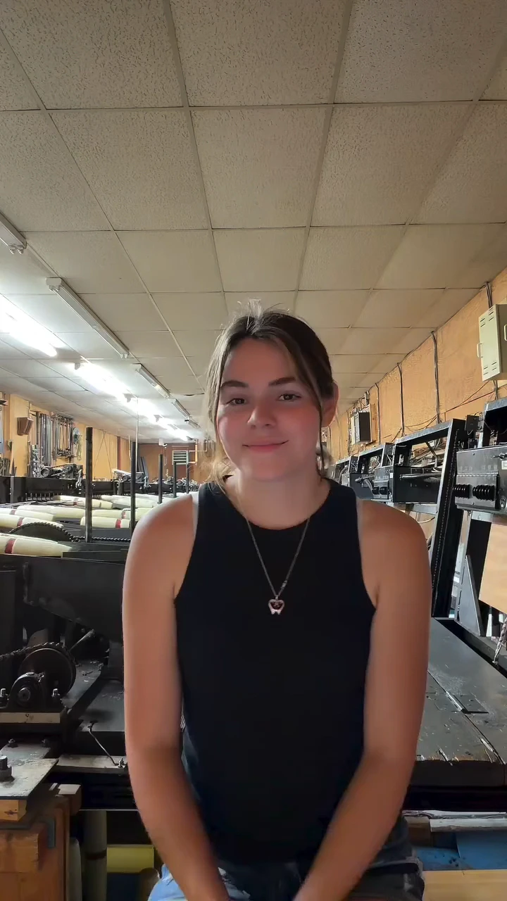 Autumn Mowery sits between rows of pin-setting machines, smiling at the camera.